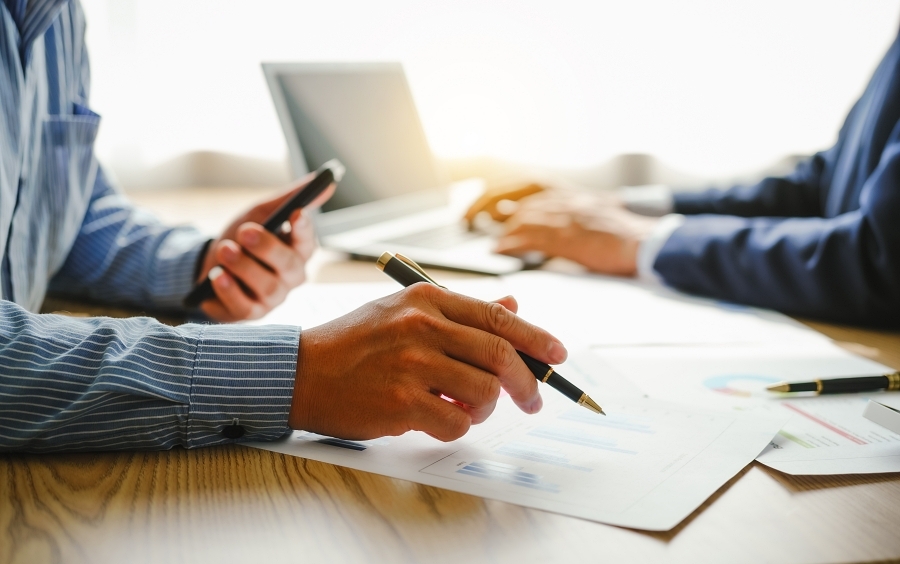 Desk-bound businessman calculates figures, verified accounts, and collaborates in discussions. Proficient in using calculators, aiding each other, and managing annual tax accounts in the audit office